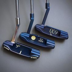 three different types of golf putters sitting next to each other on a gray surface