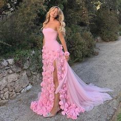 a woman in a pink dress posing for the camera with flowers on her skirt and high heels