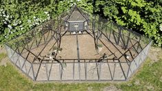 an aerial view of a small greenhouse in the middle of some grass and trees with white flowers