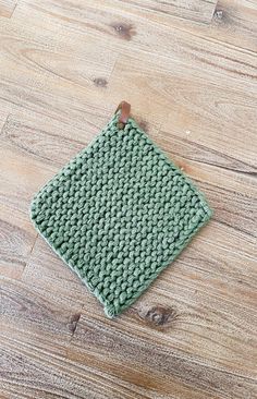 a green knitted placemat sitting on top of a wooden floor