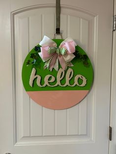 a door hanger with the word hello painted on it and two bows attached to it