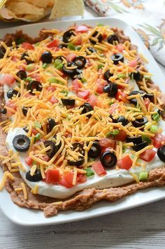 a pizza topped with black olives, tomatoes, cheese and other toppings on a white plate