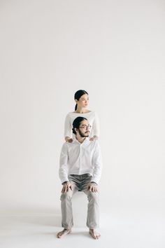 a man sitting on the back of a woman's head in front of a white background