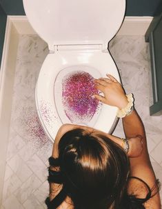 a woman is sitting on the toilet with her hands in the bowl and sprinkles all over it