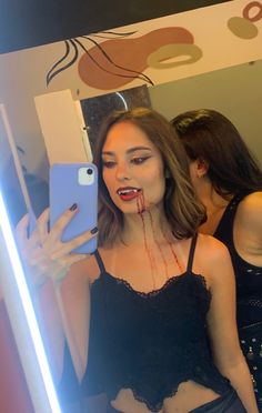 a woman with blood dripping from her mouth taking a selfie in front of a mirror