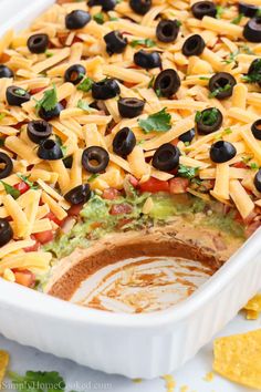 a casserole dish filled with cheese, black olives and guacamole