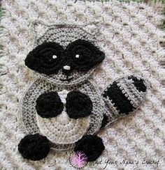 two crocheted raccoon appliques sitting on top of a blanket