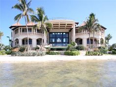 a large white building sitting on top of a beach next to palm trees and water