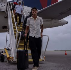 a man is walking up the stairs to an airplane with his luggage and smiling at the camera