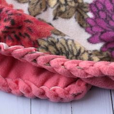 the pink flowered blanket is laying on top of white wood flooring and has been folded over