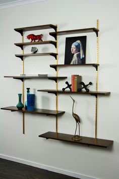 a shelf with books, vases and other items on it in a white walled room