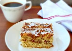 a piece of cake sitting on top of a white plate next to a cup of coffee