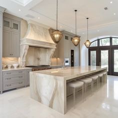 a large kitchen with marble counter tops and an island in front of two ovens