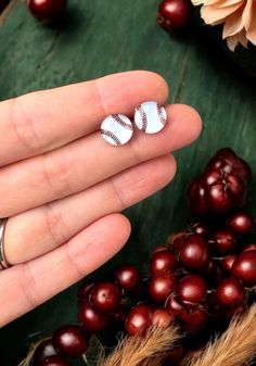 a person is holding two small baseball studs in their hand next to some berries