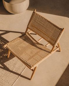 a chair sitting on top of a rug next to a cement planter in the sun