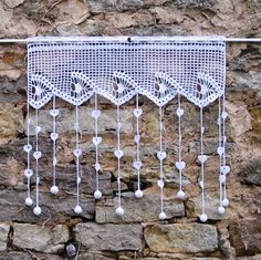 a white crocheted curtain hanging on a stone wall