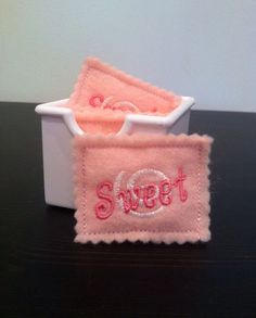 two pink towels with the word sweet on them sitting in a white container that says,