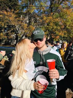 a man and woman kissing each other in front of a crowd at an outdoor event