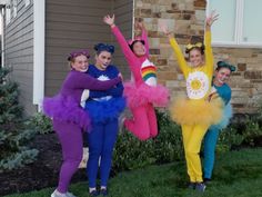 three girls in costumes are posing for the camera while one girl is holding her arms up