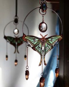 a wind chime with two butterflies hanging from it's sides and some lights on the other side