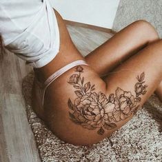 a woman laying on the floor with her stomach covered in flowers and leaves tattoo design