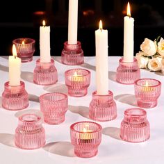 pink glass candle holders with white candles on a table