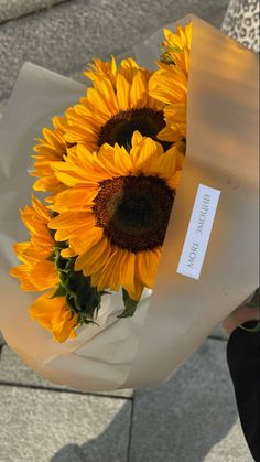 a bouquet of sunflowers is wrapped in white paper and placed on the ground