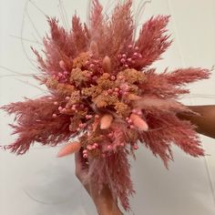 a bunch of pink flowers on top of a white table next to a person's hand