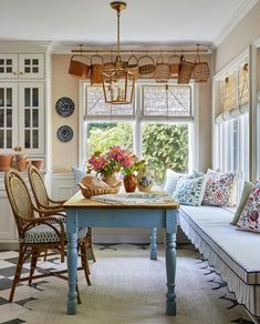 a dining room table with chairs and a bench in front of a window filled with flowers