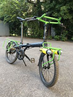 the bike is parked on the pavement in front of some trees and bushes with no one around it