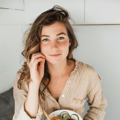 a woman sitting at a table with a bowl of food