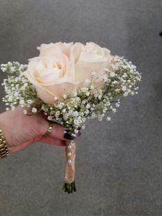 a person holding a white rose and baby's breath