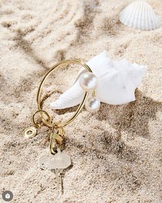 a keychain on the sand with shells and seashells