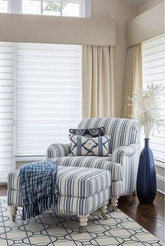 a striped chair and ottoman in front of a window with white flowers on the table