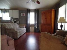 a living room filled with furniture next to a window covered in curtains and a ceiling fan