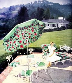 a woman sitting under an umbrella on top of a patio