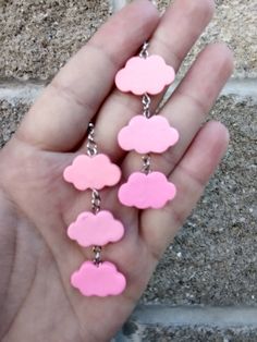 a person is holding some pink and pink clouds in their hand with chains attached to them