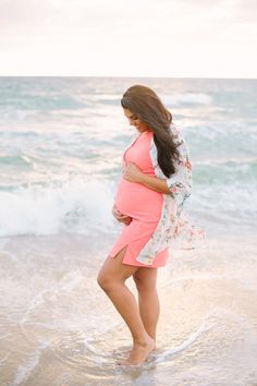 a pregnant woman standing in the surf at the beach