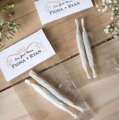 two pieces of white paper sitting on top of a wooden table next to some flowers