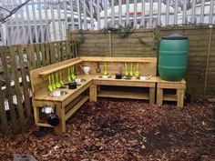 a wooden bench with pots and pans on it in the middle of a yard