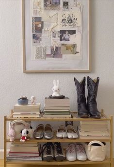 there is a shelf with books and shoes on it next to a framed picture above them