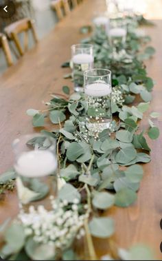 a long table with candles and greenery on it