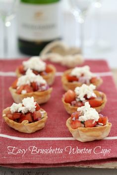 small appetizers are sitting on a red napkin next to a bottle of wine