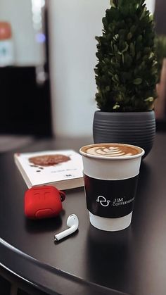 a cup of coffee sitting on top of a table next to an earbud