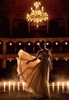 a woman in a long dress is dancing on the dance floor with candles behind her