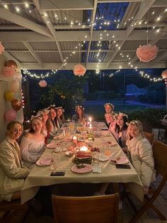 a group of women sitting at a table with candles in front of them and decorations hanging from the ceiling