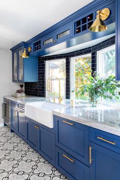 a kitchen with blue cabinets and gold pulls on the handles, counter tops, and sink