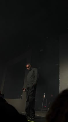 a man standing in front of a crowd on stage with his hands behind his back