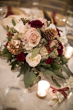 a bouquet of flowers sitting on top of a table next to candles and napkins