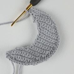 a crocheted crescent ornament hanging from a hook on a white wall